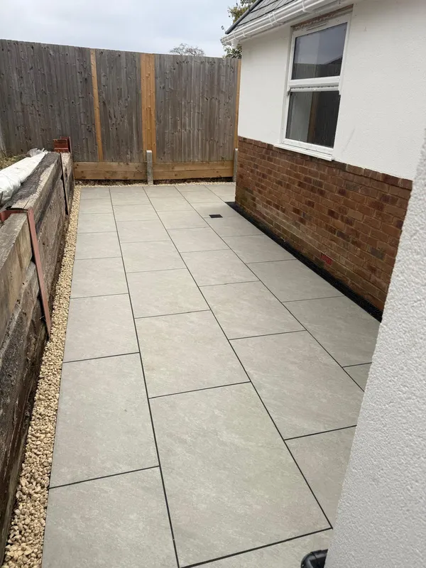 Porcelain slab pathway laid between the house wall and a brick retaining edge, Kent