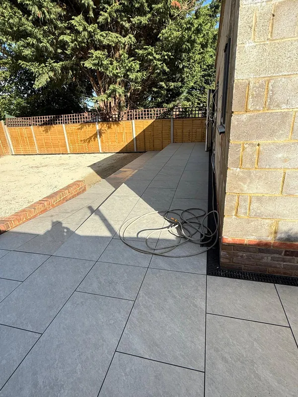 Corner of a finished porcelain slab patio with a brick edge and outside tap, Kent