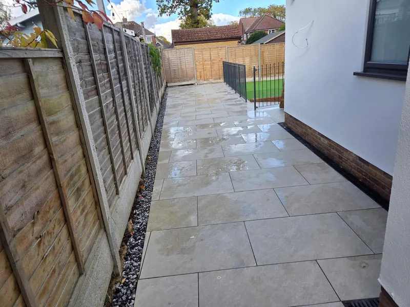 Porcelain paved pathway running between a rendered wall and a close board fence, Kent