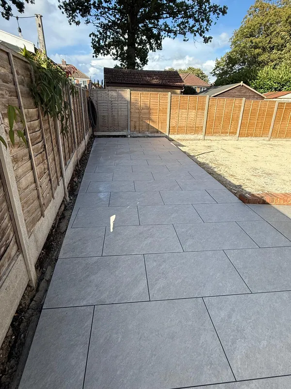 Wide grey porcelain path laid between fence panels in a Kent back garden