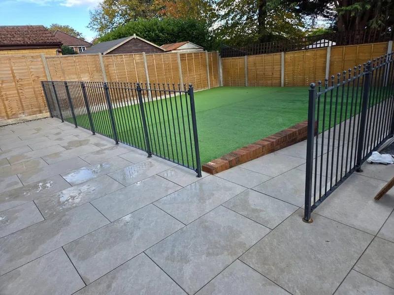 Completed porcelain slab patio with metal railings and an artificial grass lawn, Kent