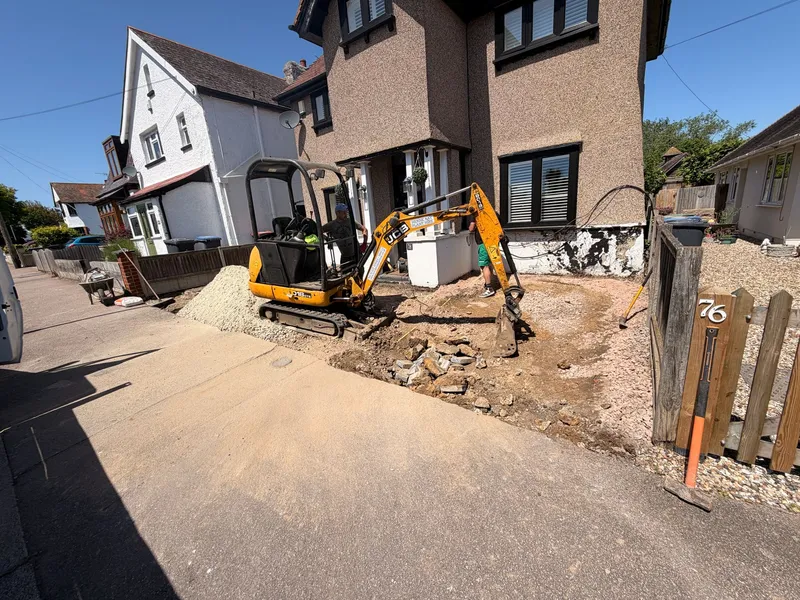 Mini digger excavating the old driveway before a new resin bound surface is laid, Kent