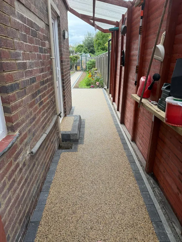 Finished golden resin bound path running alongside a brick outbuilding in Kent